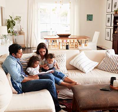 family of 4 sitting on the couch reading a book