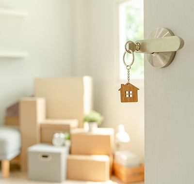 house key in the door lock with a pile of boxes in the background