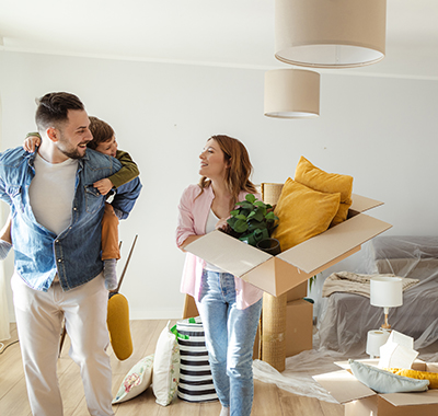 man with a kid on his back while the woman carries a box with decorations